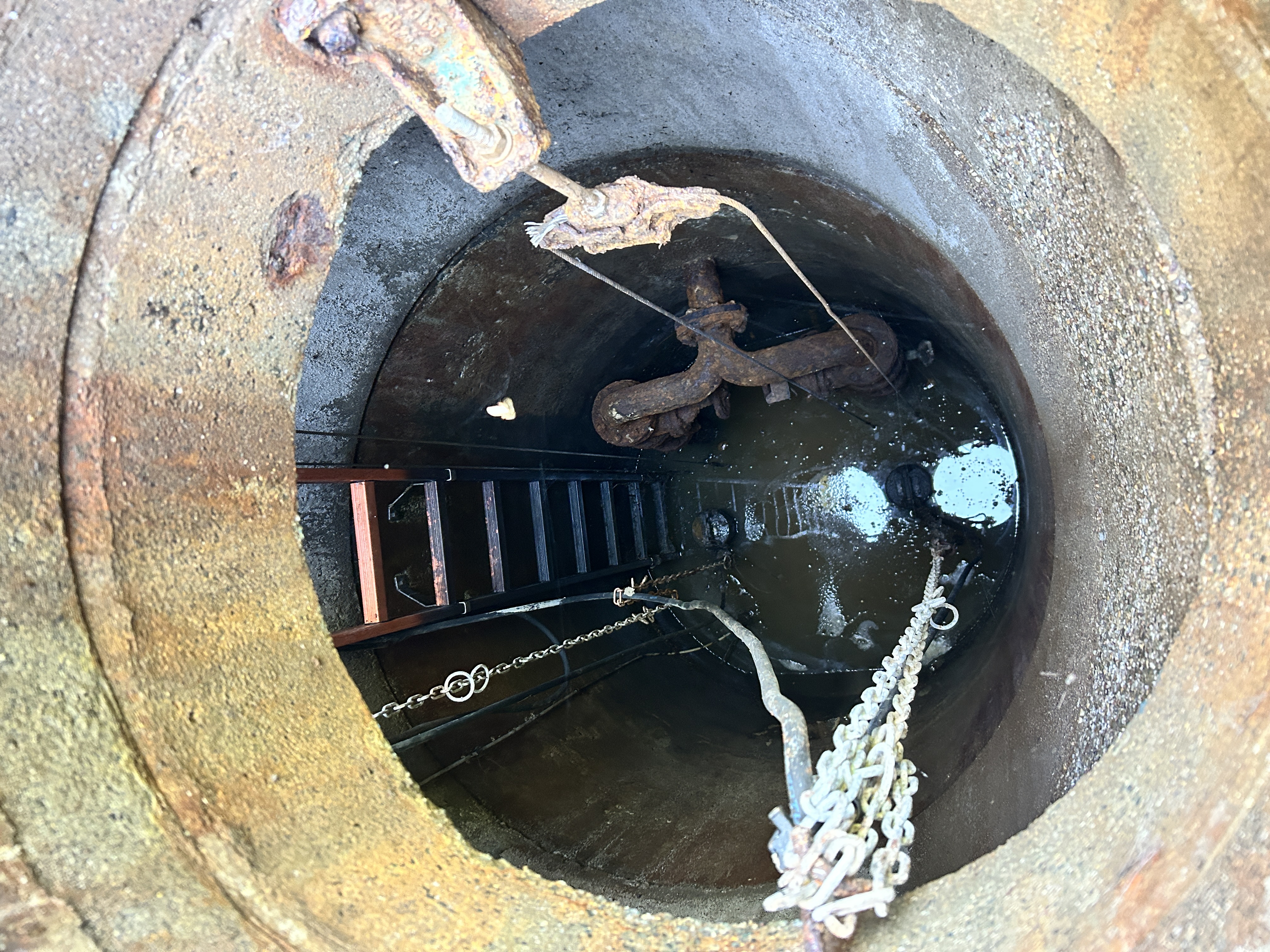 Ein tiefer Schacht mit verbauter Pumpanlage am Boden